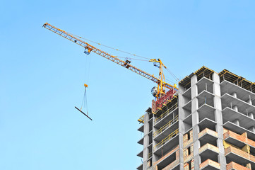 Crane and building construction site against blue sky