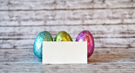 Empty Greeting Card Leaning on Colored Easter Eggs