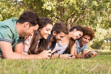 Fototapeta premium Szczęśliwi przyjaciele w parku używający telefonów