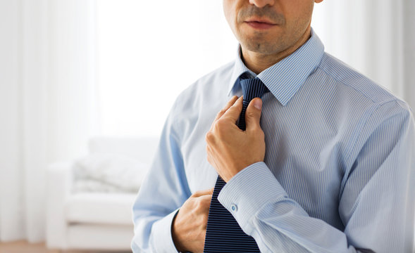 close up of man in shirt adjusting tie on neck