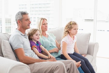 Family watching TV while sitting on sofa