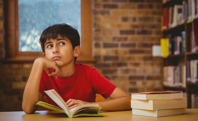 Thoughtful boy reading book in library