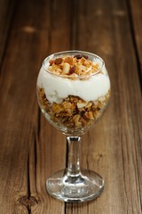 Granola in glass with yogurt on wooden background