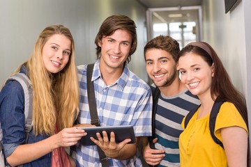 Students using digital tablet at college corridor