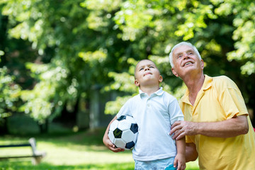 Naklejka premium grandfather and child have fun in park