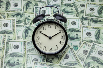 reloj despertador y billetes de cien dolares