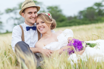 Young wedding couple walking on field.