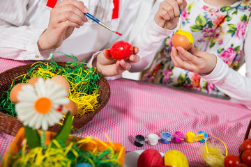 Close up of little girl and mother coloring eggs for easter
