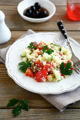 Salad with cooked couscous and vegetables on a white plate