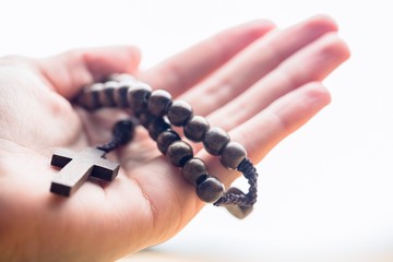 Hand holding wooden rosary beads - obrazy, fototapety, plakaty