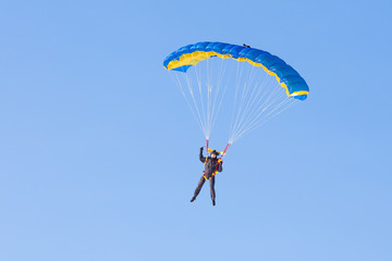 Skydiver on blue and yellow parachute