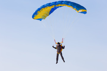 Skydiver on blue and yellow parachute closeup