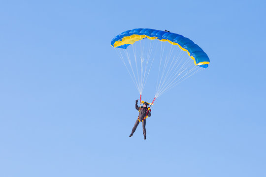 Skydiver on blue and yellow parachute