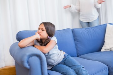 Angry little girl sitting on the couch