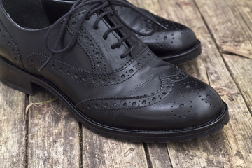 Leather shoe with shoelace on wooden background