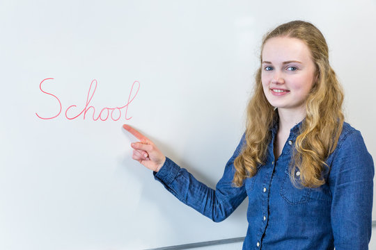teenage girl pointing at word School written on white board