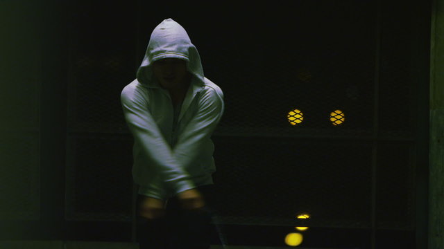 Hooded athlete skipping at night in real time