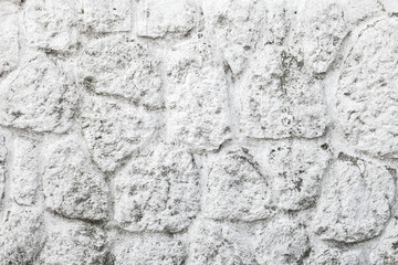 Old white painted wall made of round stones