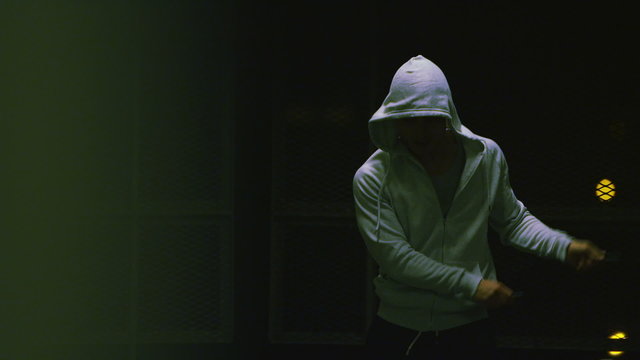 Hooded athlete skipping in urban night time environment