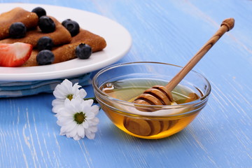 Honey dipper and pancakes on blue wooden