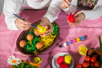 Close up of little girl and mother coloring eggs for Easter