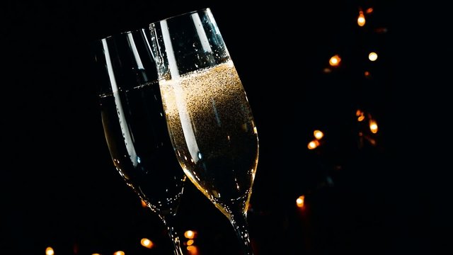 champagne flutes with bubbles on black dark light background