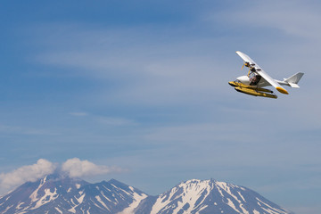 A small plane in the sky over the mountains. - obrazy, fototapety, plakaty