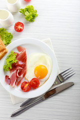 Bacon and eggs on color wooden table background
