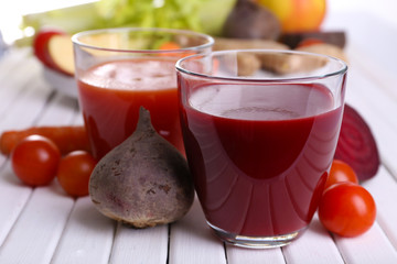 Glasses of beet juice with vegetables on wooden table closeup