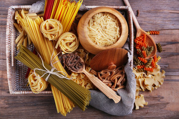 Different types of pasta in wicker basket with fabric