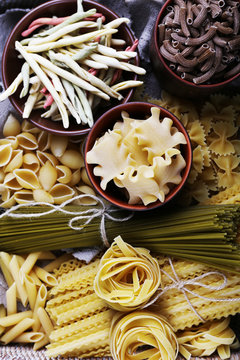 Different types of pasta in wicker basket with fabric, macro