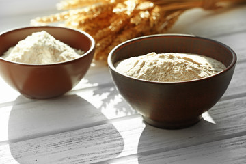 Flour in bowls on wooden planks background