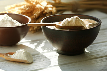 Flour in bowls on wooden planks background