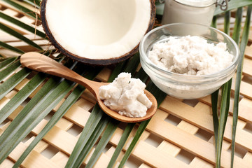 Coconut with leaf and coconut oil in jar on wooden background