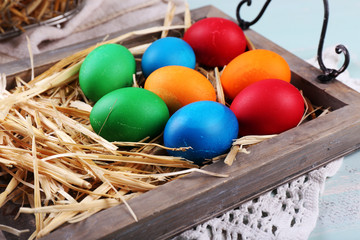 Easter eggs  on wooden tray, on colorful background