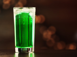 Green cocktail on table on brown background