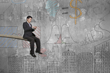 Using mobile phone businessman sitting on springboard with doodl