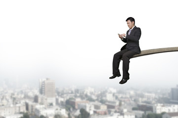 Fototapeta na wymiar Using mobile phone businessman sitting on springboard with citys