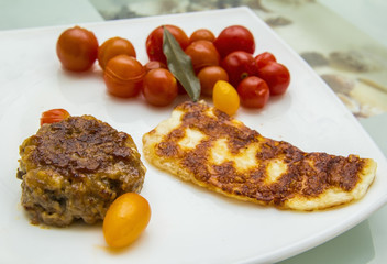 dish of fried cheese, meatballs and marinating tomatoes