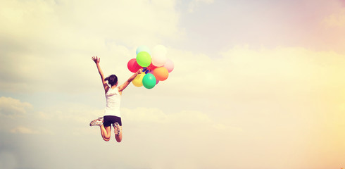 young asian woman jumping with colored balloons 