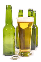 Tall glass of cold beer with green beer bottles isolated on white background photo