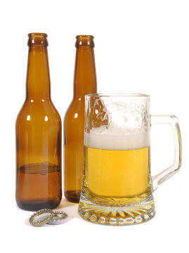 Pint glass of cold beer with brown beer bottles isolated on white background photo