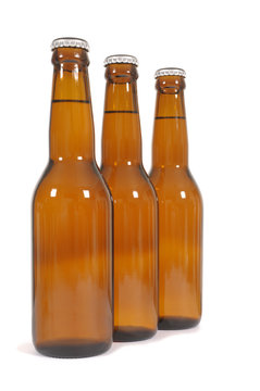 Row or line of three brown beer bottles isolated on white background photo