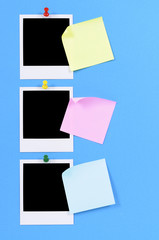 Vertical row or line of three blank polaroid style photo frame prints pinned to blue background with post it sticky note
