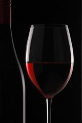 Wine glass and bottle silhouette on black background