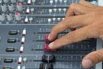 An expert adjusting audio mixing console.select focus