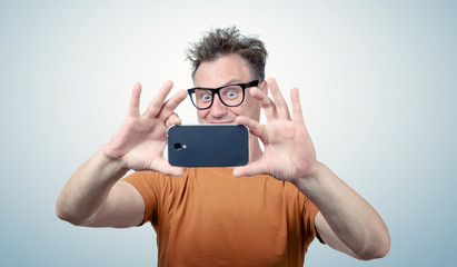 Happy man in glasses photographed by smartphone