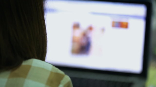 Over the shoulder shot of a woman typing on a laptop .