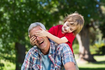 Happy little boy hiding his fatherss eyes with his hands