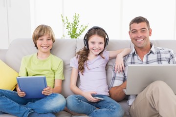 Happy man with children using technologies on sofa